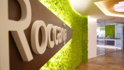 a green wall in a office with a logo at Club Esse Roccaruja in Stintino