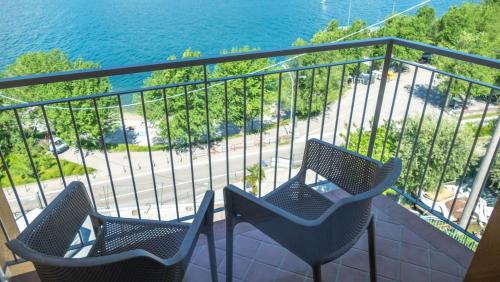 two chairs sitting on a balcony overlooking the water at Hotel Casa Marinella in Malcesine