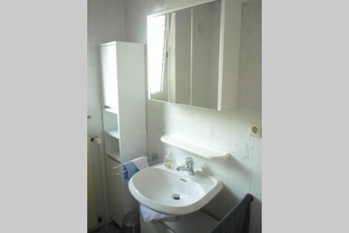 ein weißes Badezimmer mit einem Waschbecken und einem Spiegel in der Unterkunft Schlafen vor den Toren von Osnabrück für 5 Pers. 
