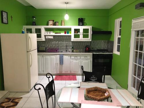 a green kitchen with a table and a white refrigerator at Tropical Apartments Tobago in Scarborough