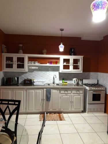 a kitchen with white cabinets and a sink and a stove at Tropical Apartments Tobago in Scarborough