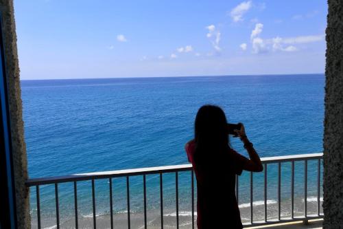 a woman taking a picture of the ocean from a balcony at Sea Palace Hotel in Marina di Fuscaldo