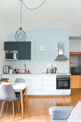 a kitchen with white cabinets and a table and chairs at Apartmán v centru in Šumperk