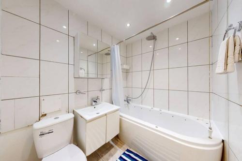 a bathroom with a toilet and a tub and a sink at Super 2 bed House wPrivateParking&PrivateGarden in London