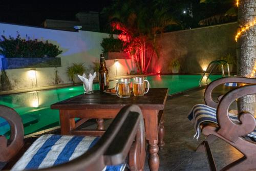 a table and chairs next to a swimming pool at night at Avon Villa in Hikkaduwa