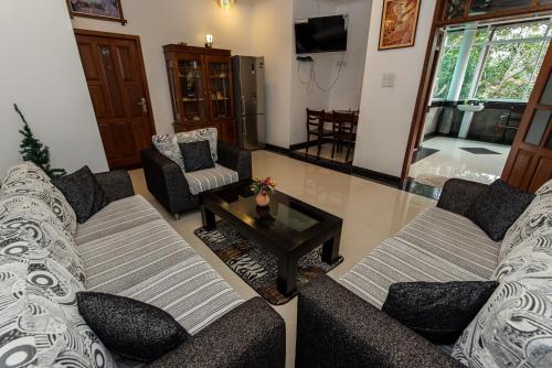 a living room with two couches and a coffee table at Avon Villa in Hikkaduwa