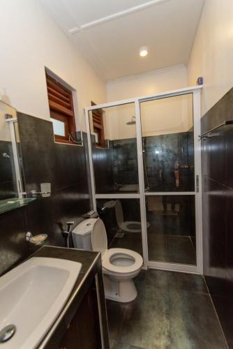 a bathroom with a toilet and a shower and a sink at Avon Villa in Hikkaduwa