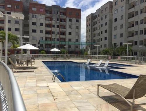 a swimming pool with chairs and tables and buildings at Apartamento Aruana a 3 Km da praia in Atalaia Velha