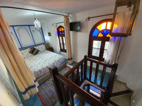 a bedroom with a bed and a staircase with a window at Riad Gharnata in Chefchaouen