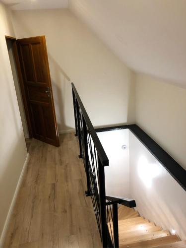 a staircase with a black rail and a wooden door at Dom Tkacki - Apartamenty - Pokoje - Jacuzzi in Kudowa-Zdrój