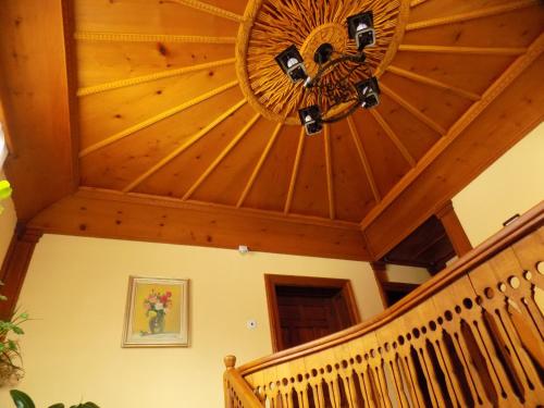 a room with a wooden ceiling with a chandelier at Dona Guest House - Horse Riding in Koprivshtitsa