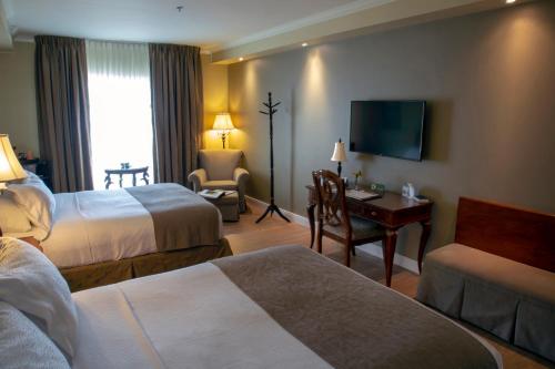 a hotel room with two beds and a television at Hotel Brossard in Brossard