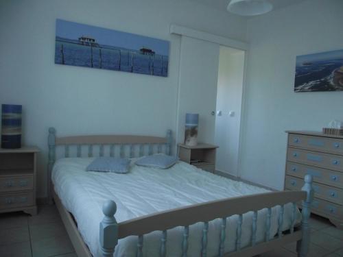a bedroom with a bed and a dresser and two pictures at Entre bassin et océan in Lège-Cap-Ferret