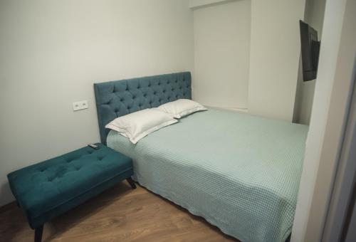 a bedroom with a blue bed and a blue ottoman at Small paradise by the old bridge in Chalkida