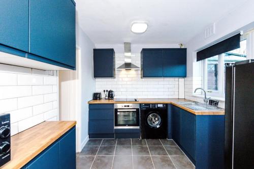 a kitchen with blue cabinets and a dishwasher at Damwood House in Liverpool