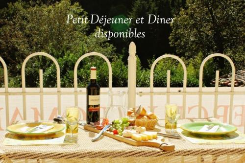a picnic table with a bottle of wine and food at Auberge Le Romarin in Valgorge