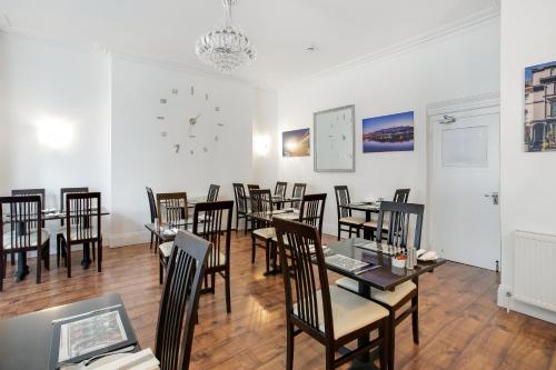 comedor con mesas y sillas y reloj en Trelawney Hotel - Guest House, en Torquay