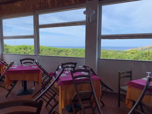 a room with tables and chairs with a view of the ocean at Club Esse Gallura in Aglientu