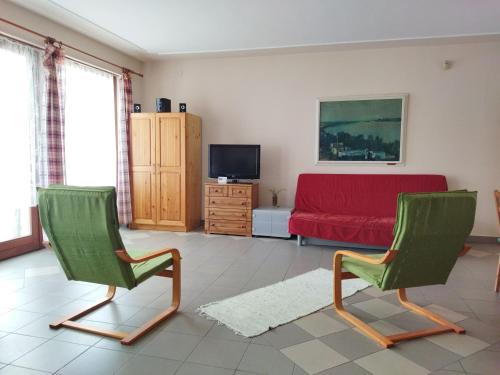 sala de estar con 2 sillas verdes y sofá rojo en Naszály Kapuja vendégház, en Kosd