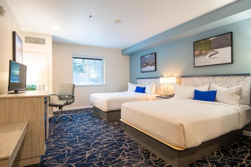 a hotel room with two beds and a flat screen tv at Gateway Hotel in Seward