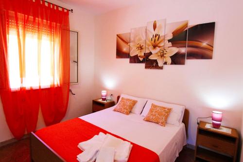 1 dormitorio con 1 cama con cortinas rojas y una pintura floral en Villetta indipendente con giardino 400m dal mare Rif. 448, en Leuca
