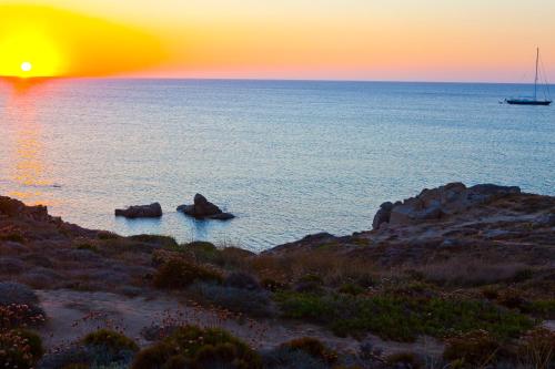 a sunset over the ocean with a boat in the water at Club Esse Gallura in Aglientu