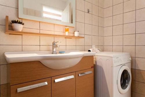 een badkamer met wastafel en wasmachine bij Beautiful Holiday House near the sea in Sissi
