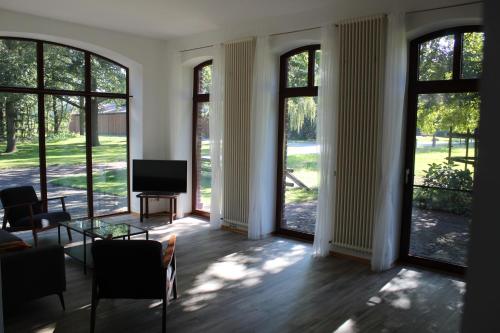 a living room with large windows and a flat screen tv at Ferienhaus auf Gut Sautmannshausen in Haselünne
