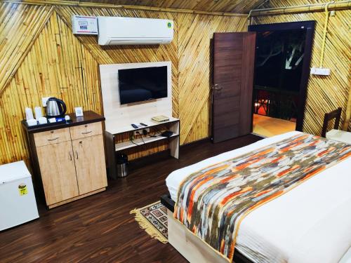 Hotel Bamboo Castle في جايبور: غرفة نوم بسرير وتلفزيون في غرفة