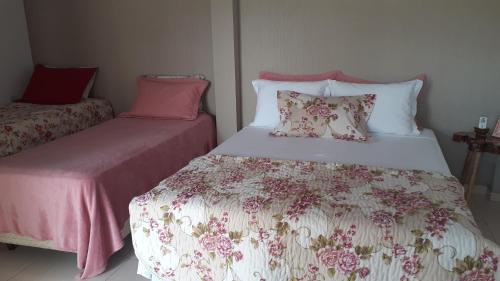 1 dormitorio con 2 camas con sábanas rosas y blancas en Pousada recantoceccataratas en Foz de Iguazú
