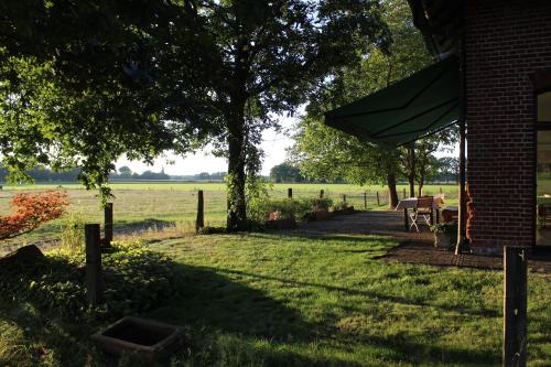 a patio with a table and a tree in a field at Ferienhaus auf Gut Sautmannshausen in Haselünne