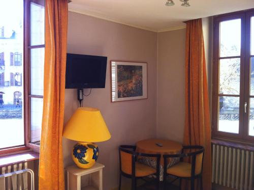 a room with a table and a lamp and windows at Hotel de Savoie in Annecy