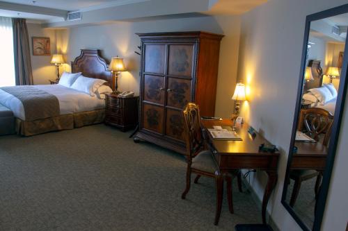 a hotel room with a bed and a desk and a mirror at Hotel Brossard in Brossard