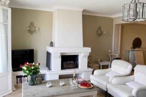 Elle comprend un salon doté d'un mobilier blanc et d'une cheminée. dans l'établissement BORD DE MER - AC, WIFI, chic, sea view, beach 2 minutes walk, à Antibes
