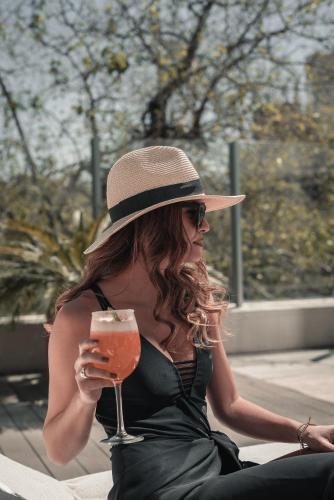 a woman wearing a hat and holding a drink at DiplomaticHotel in Mendoza