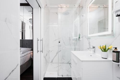 biała łazienka z prysznicem i umywalką w obiekcie Salomea Krakow apartments w Krakowie