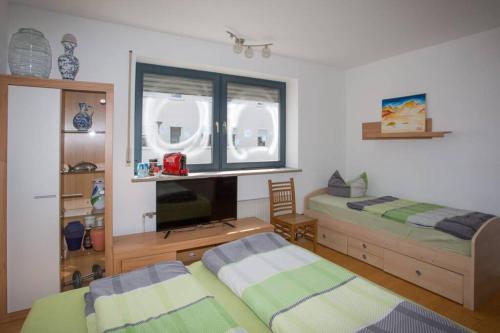 a bedroom with two beds and a desk and a tv at Ruhiges Gästezimmer am Stadtpark in Schwabach