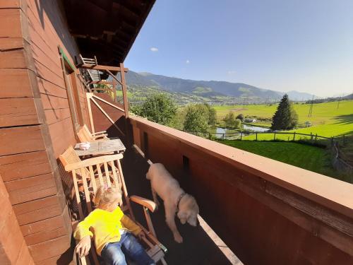 a woman sitting on a porch with a dog at Apartments Teglbauernhof, Hütte, Chalet, Mobilheim, Appartement, Ferienwohnung, Pension, Urlaub in Uttendorf
