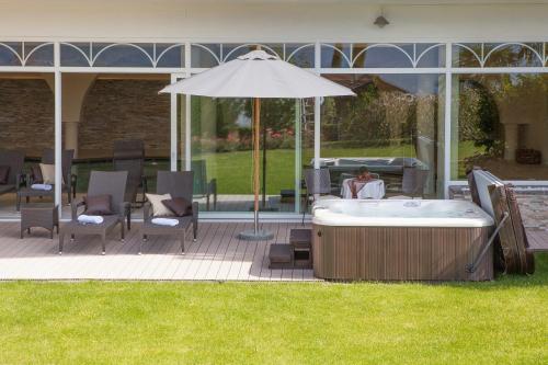 a hot tub and chairs and an umbrella on a patio at Hotel Garni Katnau in Schenna