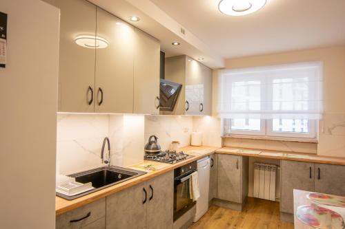 uma cozinha com armários brancos e um lavatório em Apartament Omega I em Giżycko