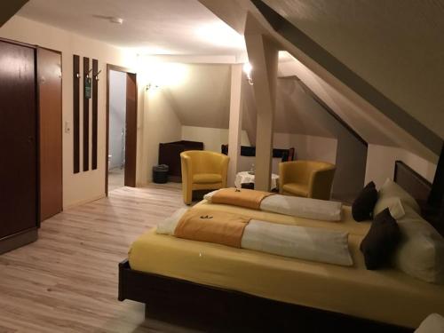 a bedroom with a large bed and two yellow chairs at Hotel Schöne Aussicht in Weißenfels
