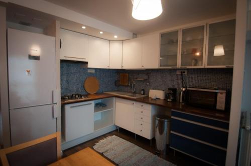 cocina con armarios blancos y nevera en Lappartement en Saint Cyprien Plage