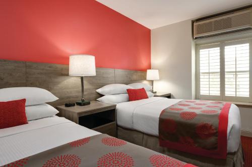 two beds in a hotel room with red walls at Ramada by Wyndham Oakland Downtown City Center in Oakland