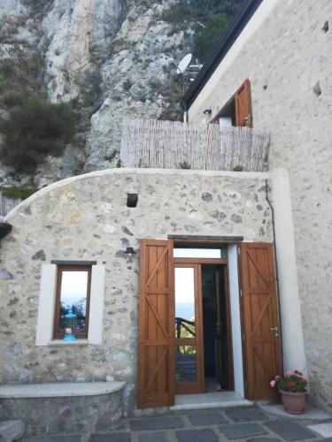 a stone building with wooden doors and windows at Il Nido Del Falco - Art house with terrace and sea view in Furore