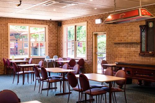 a dining room with tables and chairs and a piano at New Crown Hotel Motel in Hay