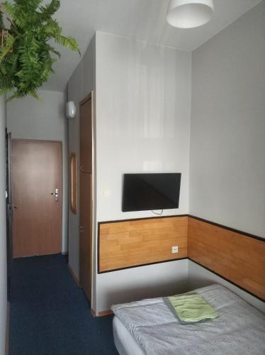 Habitación con cama y TV de pantalla plana en la pared. en Hotel Mark en Marki