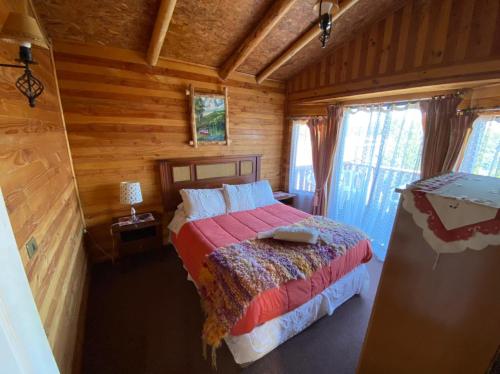 a bedroom with a bed in a wooden cabin at Cabañas y Hostel Isla Magica in Ancud