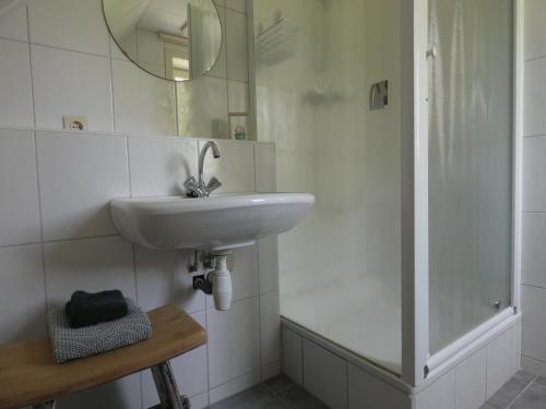 a white bathroom with a sink and a shower at 't Uilengat in Retranchement