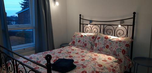 a bedroom with a bed with a floral bedspread and a window at Cosy house, 3 bedrooms, private parking, wifi, patio in Norwich