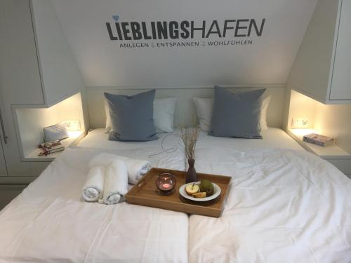 a bed with a tray with towels and a plate of fruit at DünenHuuskes Spiekeroog in Spiekeroog